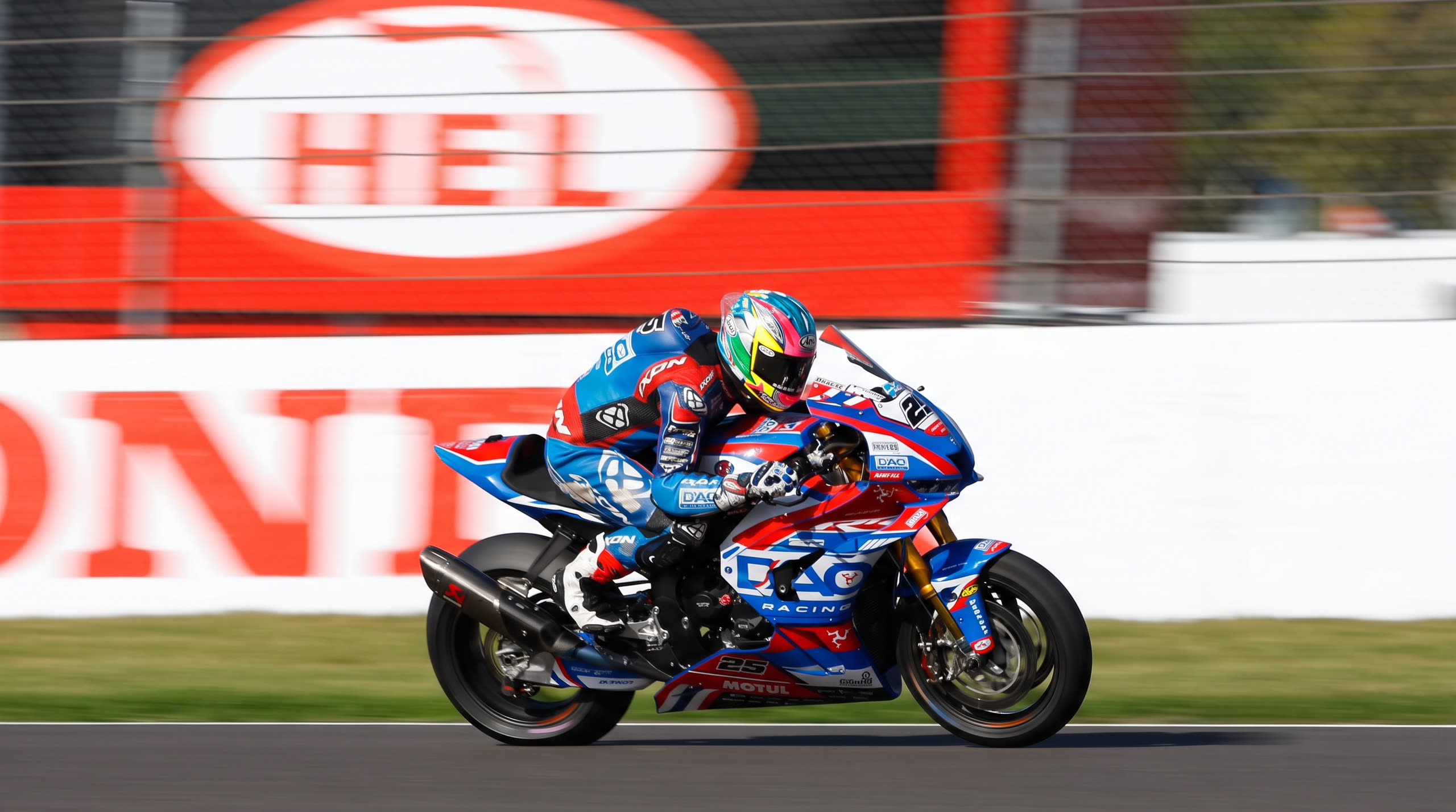 Superbike i full fart forbi en HEL-reklame langs banen